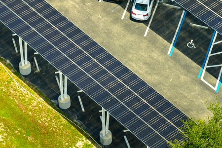 Aerial view of solar panels installed as shade roof over parking lot for parked cars for effective generation of clean electricity. Photovoltaic technology integrated in urban infrastructureの写真素材