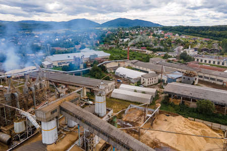 Aerial view of wood processing plant with smokestack from production process polluting environment at factory manufacturing yardの写真素材