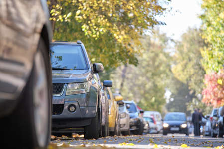 City traffic with many cars parked in line on street sideの写真素材