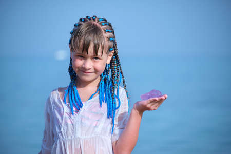 Happy smiling teenage girl holds out her hand to camera with caught pink transparent Jellyfishの写真素材