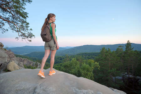 Hiker woman walking on mountain footpath enjoying evening nature. Lonely female traveler traversing wilderness trail. Healthy lifestyle conceptの写真素材