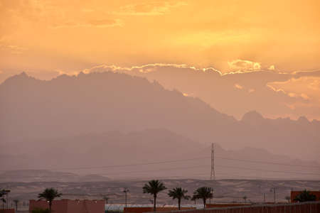 Sunset landscape with remote hotel complex against dark mountain peaks in egyptian desertの写真素材