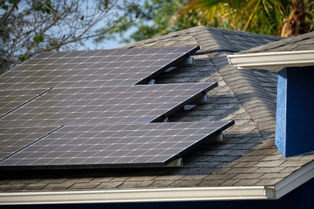 Residential house with rooftop covered with solar photovoltaic panels for producing of clean ecological electrical energy in suburban rural area. Concept of autonomous homeの写真素材