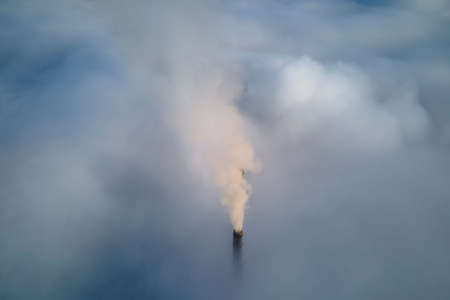 Coal power plant high pipes with black smoke moving upwards over clouds polluting atmosphere....