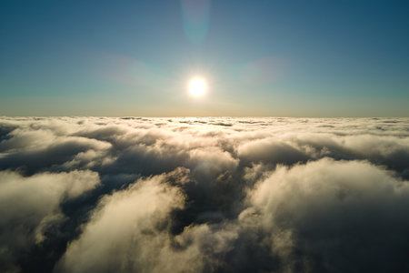 Aerial view from above at high altitude of dense puffy cumulus clouds flying in evening. Amazing sunset from airplane window point of viewの写真素材