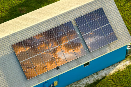 Aerial view of typical american building roof with rows of blue solar photovoltaic panels for...