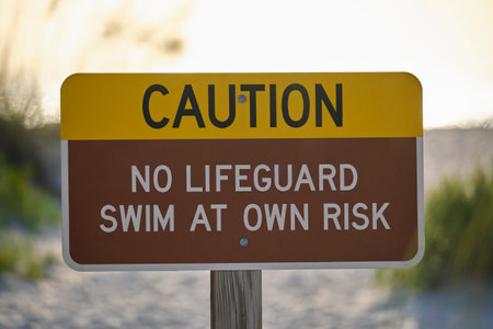 Warning sign poster on sea side beach saying that there is no lifeguard on duty