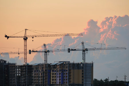 Tower lifting cranes at high residential apartment buildings construction site. Real estate...