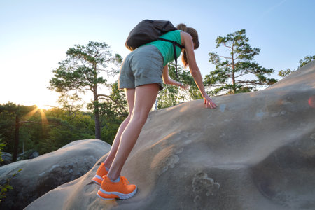 Hiker woman clambering on rocky mountain footpath in evening nature. Lonely female traveler traversing hard wilderness trail. Healthy lifestyle and sport conceptの写真素材