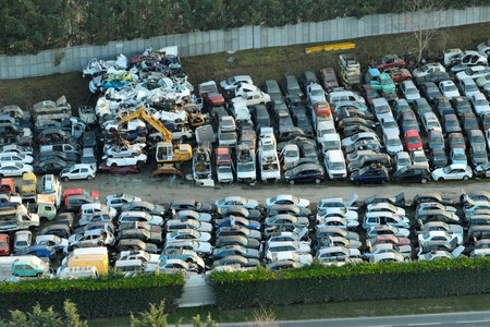 Aerial view of big parking lot of junkyard with rows of discarded broken cars. Recycling of old...
