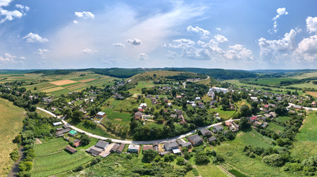 Aerial landscape view of green cultivated agricultural fields with growing crops and distant village housesの写真素材