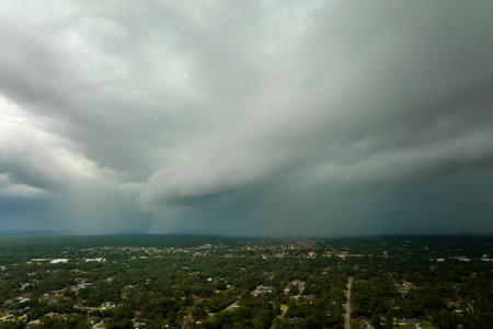 Dark stormy clouds forming on gloomy sky before heavy rainfall over suburban town area