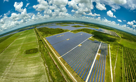 Aerial view of sustainable electric power plant between agricultural farm fields with solar...