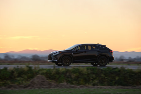 SUV car driving fast on intercity road at sunset. Highway traffic in eveningの写真素材