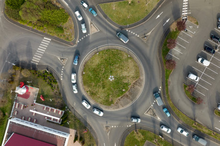 Aerial view of road roundabout intersection with fast moving heavy traffic. Urban circular...