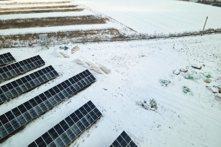 Aerial view of sustainable electrical power plant with solar photovoltaic panels covered with snow in winter for producing clean energy. Concept of low effectivity of renewable electricity in northの写真素材