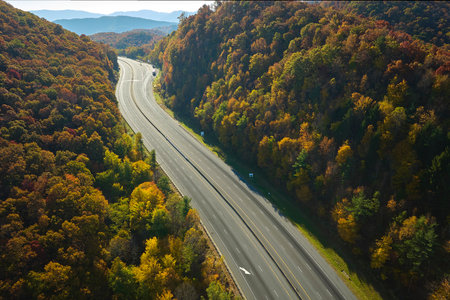 View from above of empty deserted I-40 freeway route in North Carolina leading to Asheville thru Appalachian mountains with yellow fall woods. Interstate transportation conceptの写真素材