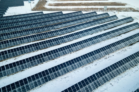 Aerial view of electrical power plant with solar panels covered with snow melting down in winter end for producing clean energy. Concept of low effectivity of renewable electricity in northern regionの写真素材