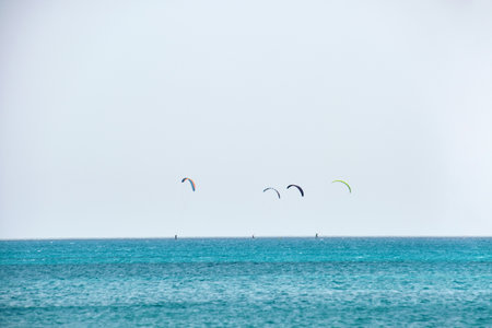 People sportsmen windsurfing and kite surfing in blue ocean water. Summer extreme exotic sport...
