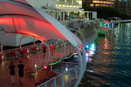 People enjoying time walking on pedestrian riverwalk trail alongside river water in downtown district of Tampa city in Florida, USA. Recreational area in modern american megapolisの写真素材