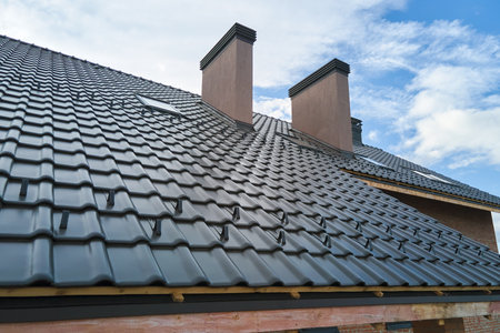 Closeup snow guard for safety in winter on house roof top covered with ceramic shingles. Tiled covering of buildingの写真素材