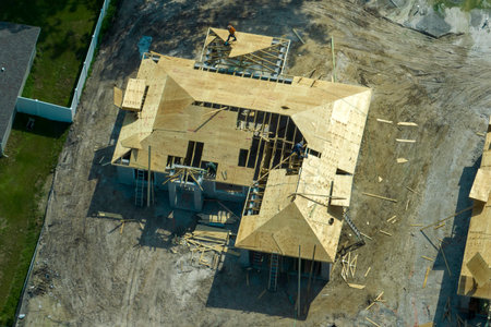 Professional builders working on roof construction of unfinished suburban home with wooden frame structure in Florida rural area. Concept of housing development in Americaの写真素材