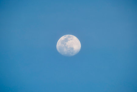 Bright full moon on blue sky during daylight. Round lunar discの写真素材