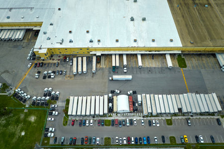 Big corporate shipment center with many cargo semi trucks unloading and uploading retail products...