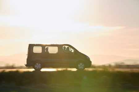 Passenger van driving fast on intercity road at sunset. Highway traffic in eveningの写真素材