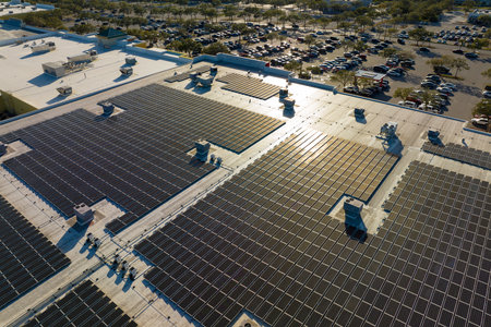 Aerial view of blue photovoltaic solar panels mounted on shopping mall building roof for producing...