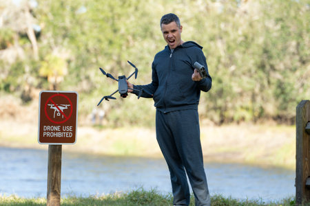 Man is sad that he is not allowed to fly his quadcopter state park no drone area. Operator is...