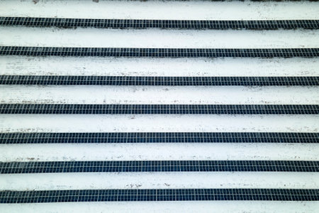 Aerial view of electrical power plant with solar panels covered with snow melting down in winter end...