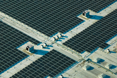 Production of sustainable energy. Aerial view of solar power plant with blue photovoltaic panels mounted on industrial building roof for producing green ecological electricityの写真素材