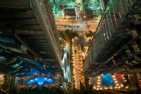 View from above of brightly illuminated high skyscraper hotel with swimming pool recreational area in downtown of Sunny Isles Beach city in Florida, USA. American tourist urban district at nightの写真素材