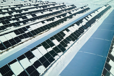 Aerial view of electrical power plant with solar panels covered with snow melting down in winter end for producing clean energy. Concept of low effectivity of renewable electricity in northern regionの写真素材