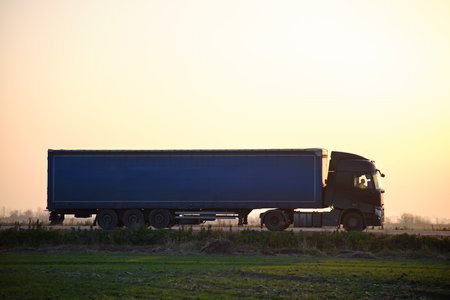 Semi-truck with cargo trailer driving on highway hauling goods in evening. Delivery transportation and logistics conceptの写真素材