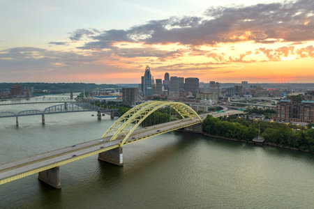 Highway traffic with driving cars on bridge in downtown district of Cincinnati city in Ohio, USA. American city skyline with brightly illuminated high commercial buildings at sunsetの写真素材