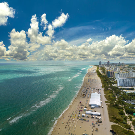Tourism infrastructure in southern USA. South Beach sandy surface with tourists relaxing on hot Florida sun. Miami Beach city with high luxury hotels and condosの写真素材
