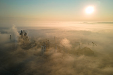 Aerial view of cement factory with high concrete plant structure and tower crane at industrial...