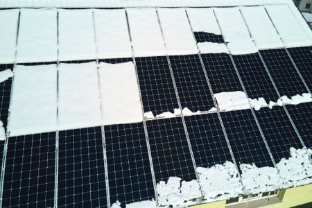 Aerial view of house roof with solar panels covered with snow melting down in winter end for producing clean energy. Concept of low effectivity of renewable electricity in northern regionの写真素材