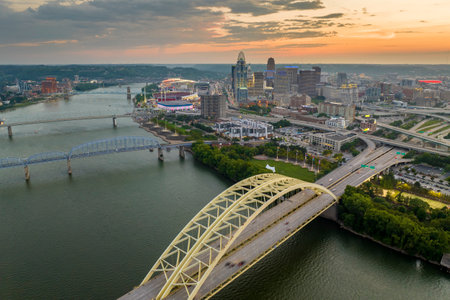 Downtown district of Cincinnati city in Ohio, USA at sunset with driving cars traffic on Daniel Carter Beard Bridge and brightly illuminated high skyscraper buildings. American travel destinationの写真素材