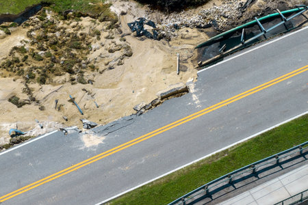 Repair of destroyed bridge after hurricane flood in Florida. Reconstruction of damaged road after flooding water washed away asphalt. Construction roadwork siteの写真素材