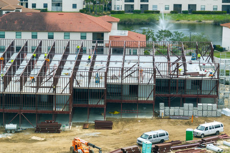 Construction works on metal walls of commercial building. Blue collar workers at large site with...