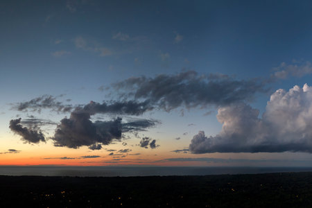 Amazing sunset skyscape. Evening sky with bright colorful orange and yellow clouds over dark landscapeの写真素材