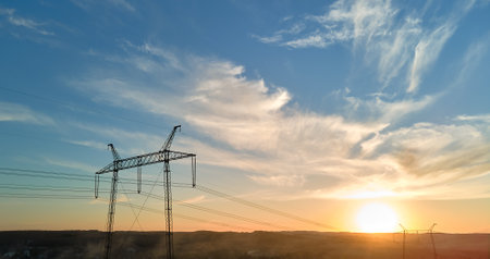 Dark silhouette of high voltage tower with electric power lines at sunrise. Transmission of electric energy conceptの写真素材