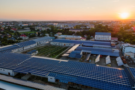 Aerial view of solar power plant with blue photovoltaic panels mounted on industrial building roof...