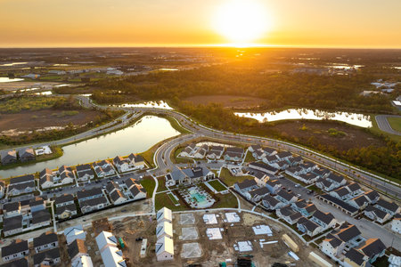 Unfinished frames of inexpensive homes with wooden roof beams under construction. Development of residential housing in US suburbs. Real estate market in the USAの写真素材