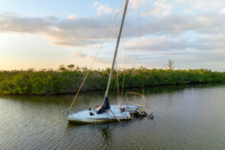 Capsized sunken sailing boat left forsaken on shallow bay waters after hurricane Ian in Manasota, Floridaの写真素材