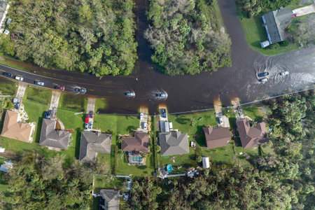 Flooded road in Florida after heavy hurricane rainfall. Aerial view of evacuating cars and surrounded with water houses in suburban residential areaの写真素材