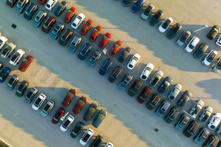Large parking lot of local dealer with many brand new cars parked for sale. Development of american...